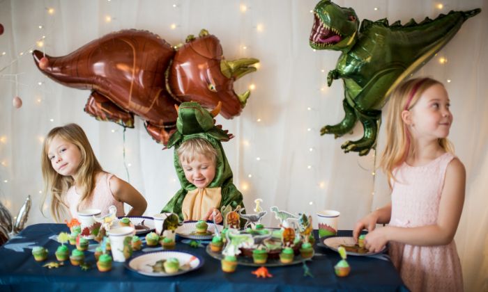 Kinder die an einem Dinosaurier Motto Geburtstag teilnehmen