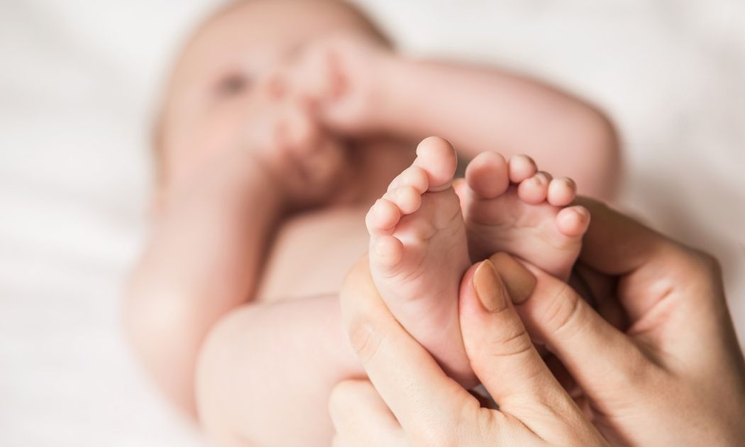 Frauenhände massieren Babyfüße © llhedgehogll/Adobe Stock